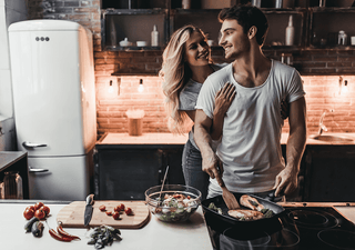 Para młodych zakochanych ludzi gotująca wspólnie obiad w loftowej kuchni