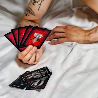 Wytatuowana męska dłoń trzyma kilka kart z gry dla par arkana miłości.